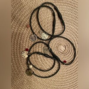 5 black rubber bracelets with charms.
